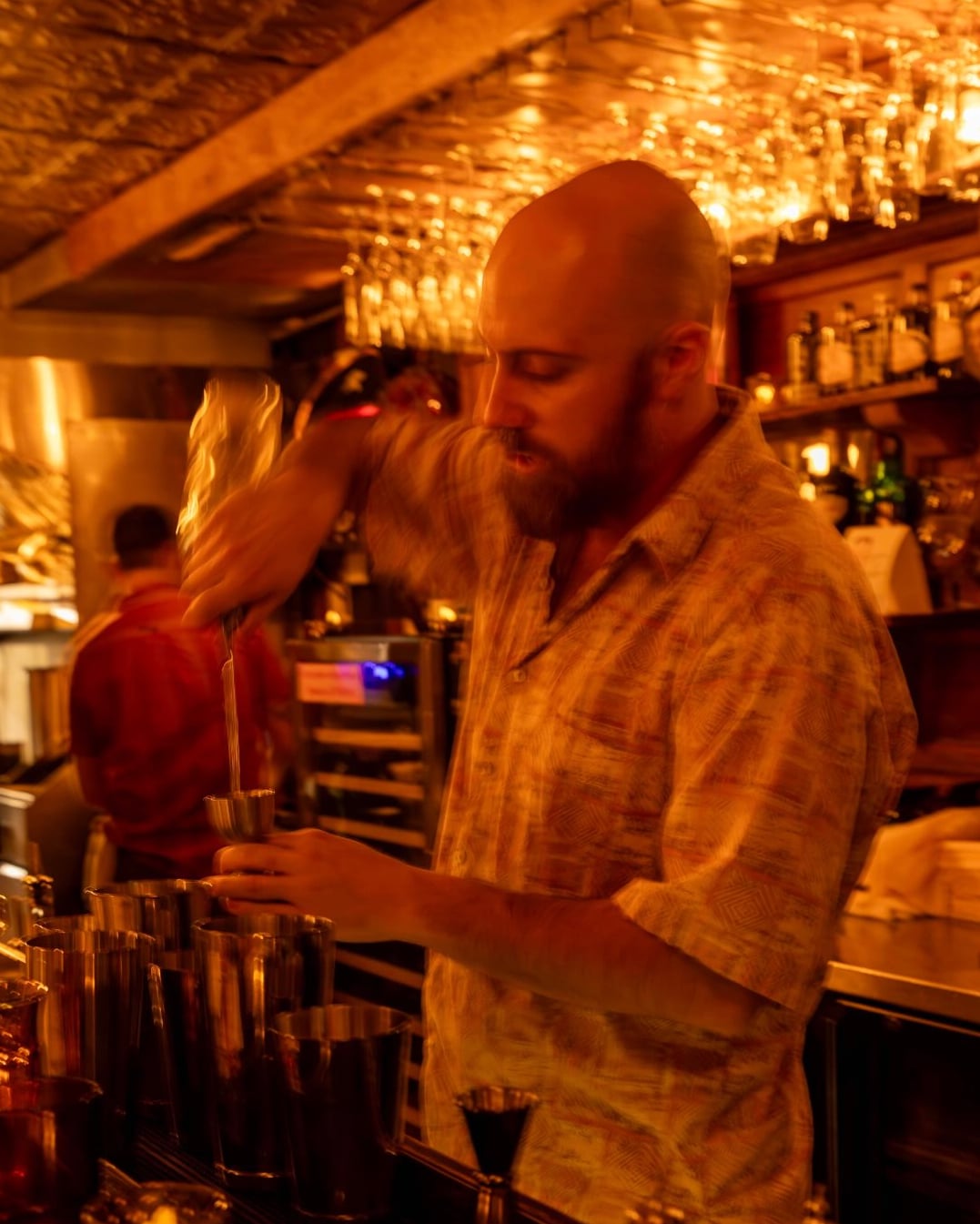 Bartender crafting drinks at the polished bar counter.
