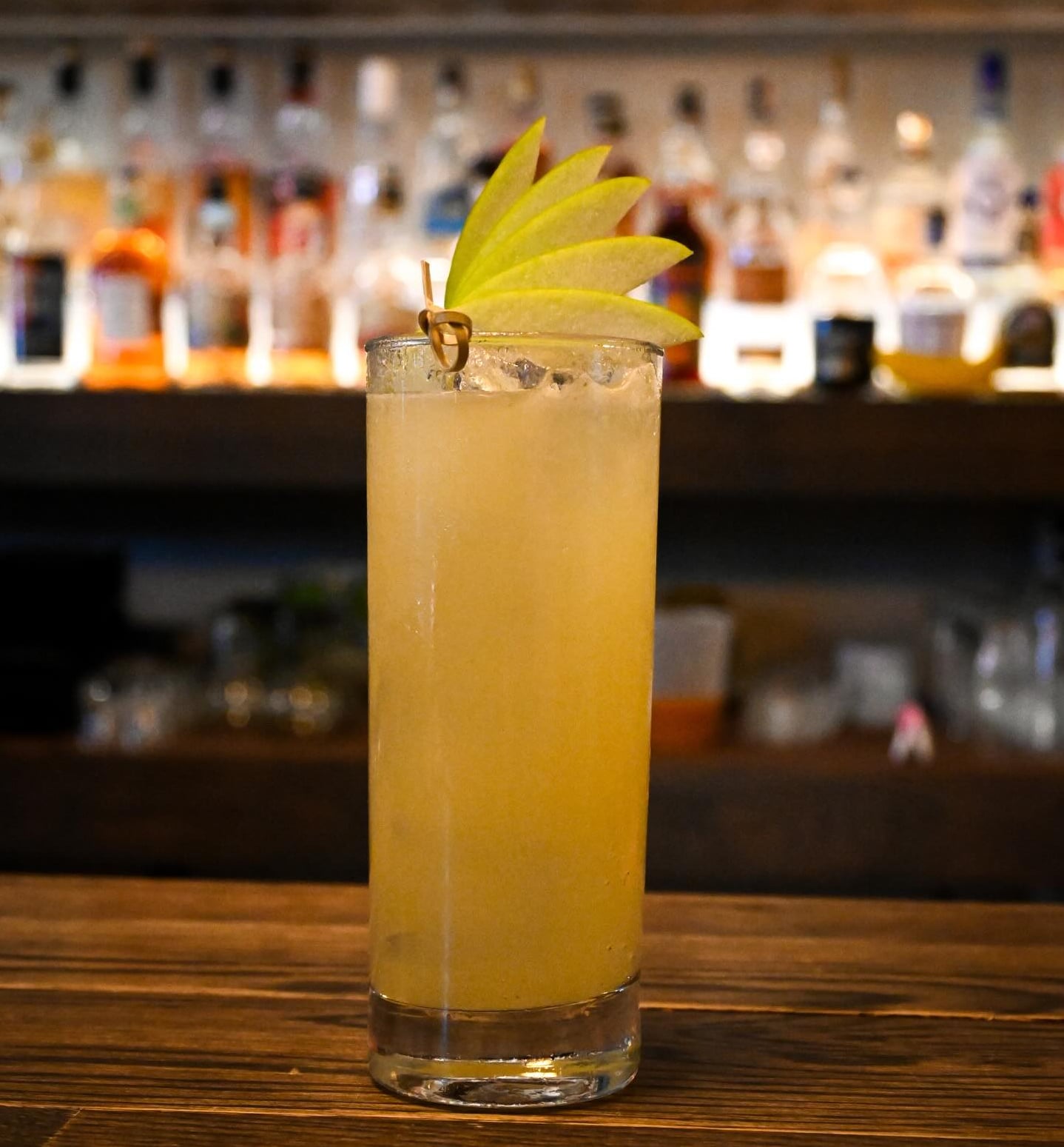 Signature house cocktail with pineapple garnish and backbar backdrop