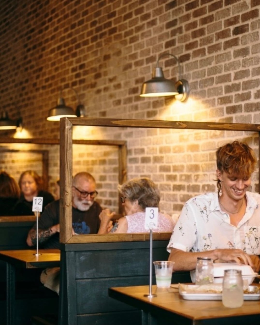 Cozy dining area with reclaimed wood booths and industrial lighting against an exposed brick wall.