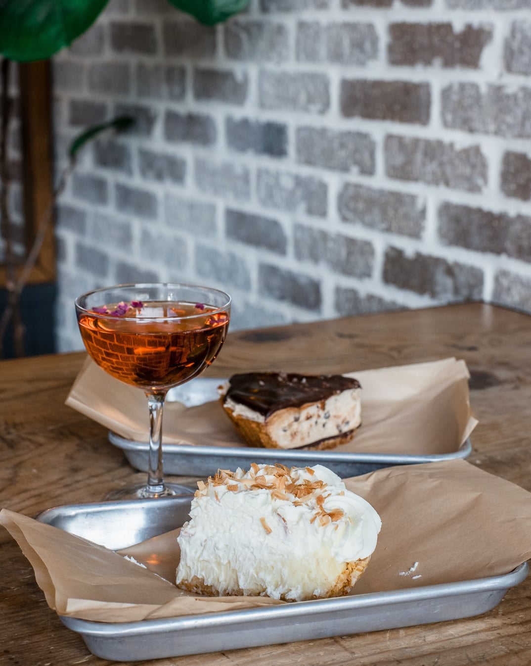Cocktail and desserts served on rustic metal trays.