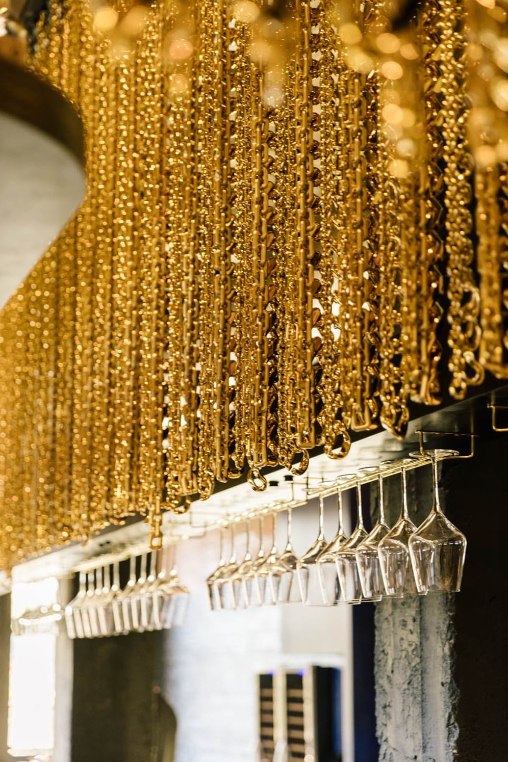Glassware suspended beneath Golden Hour's signature gold chain installation.