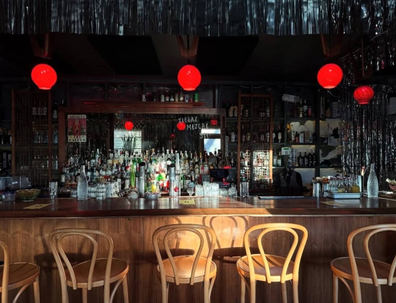 Wooden bar and stocked backbar under red globe lights