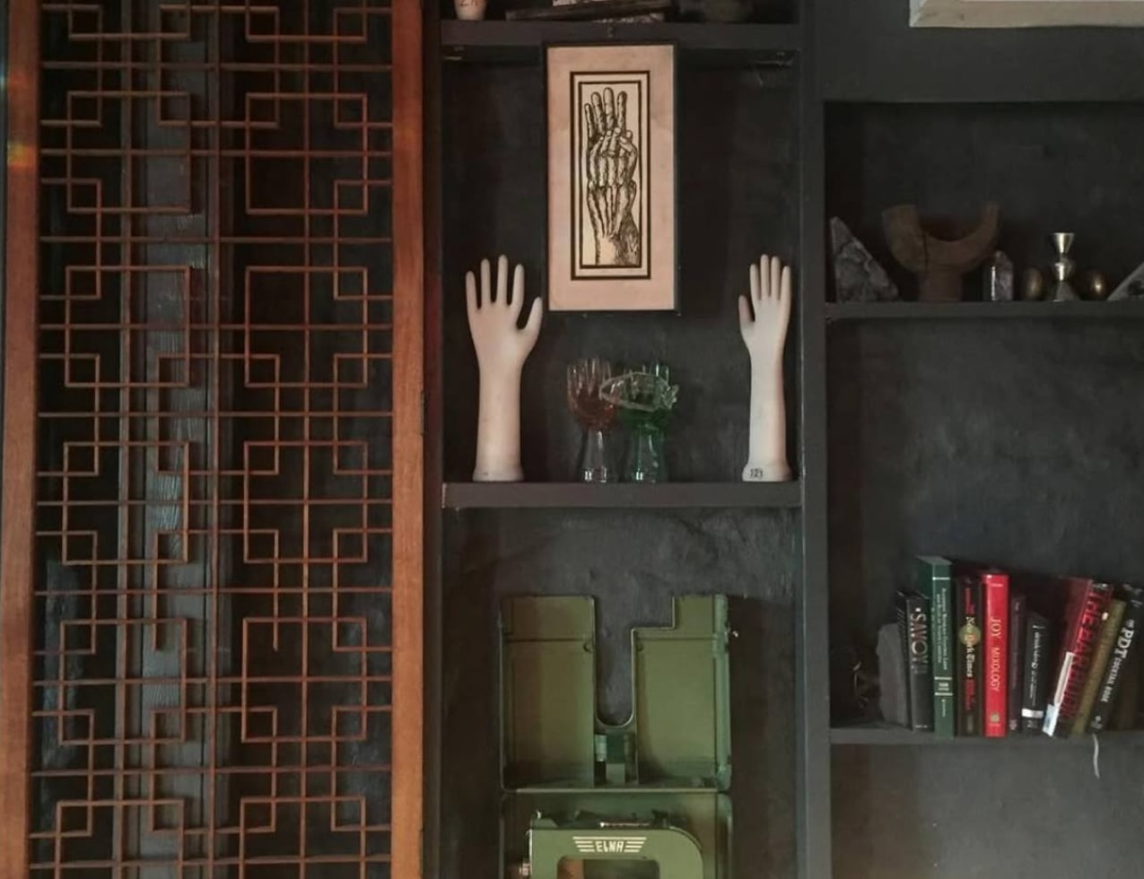 Hand sculptures and books beside a wooden screen