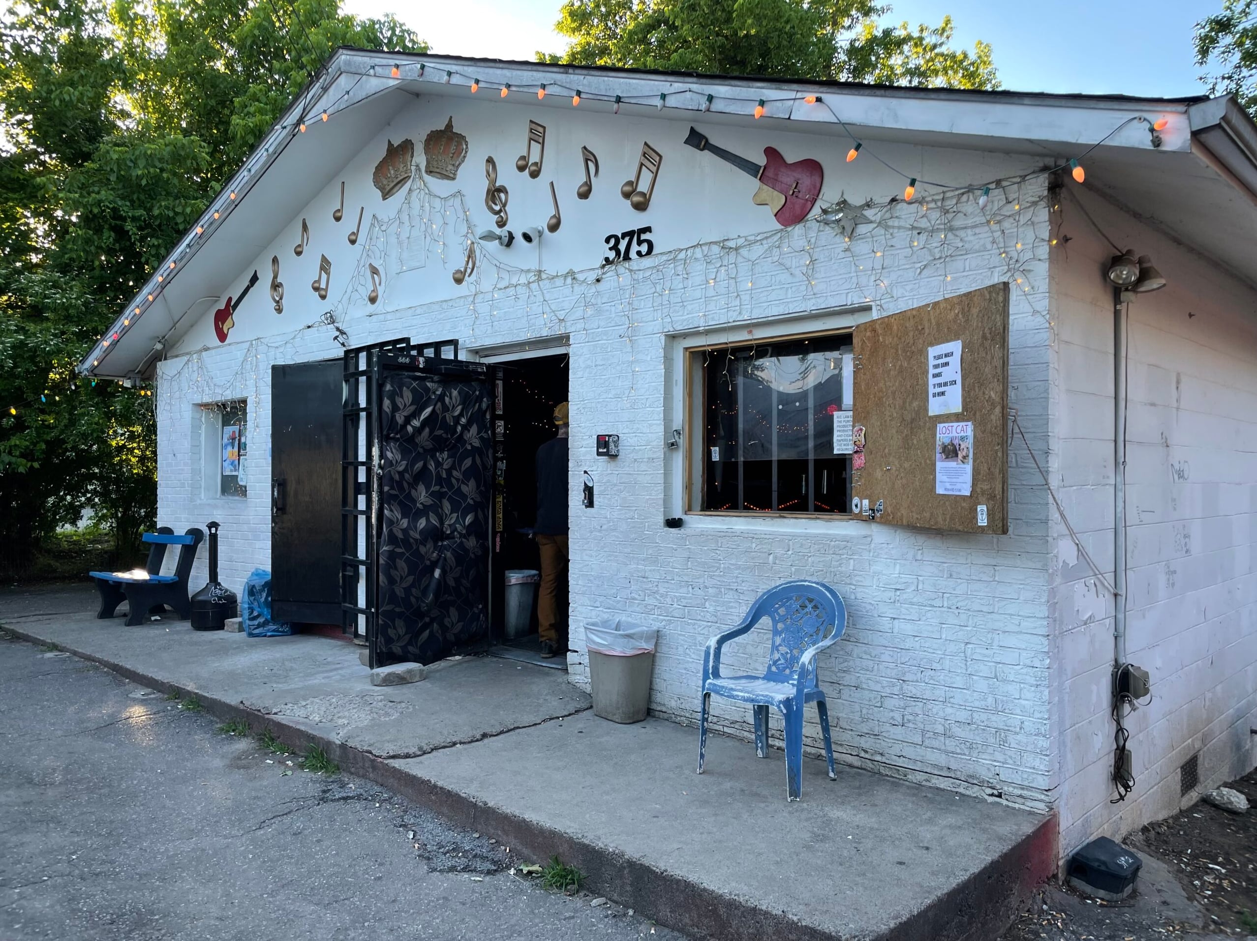 The Double Crown exterior at 375 Haywood Road, with musical note murals and string lights on the white brick facade