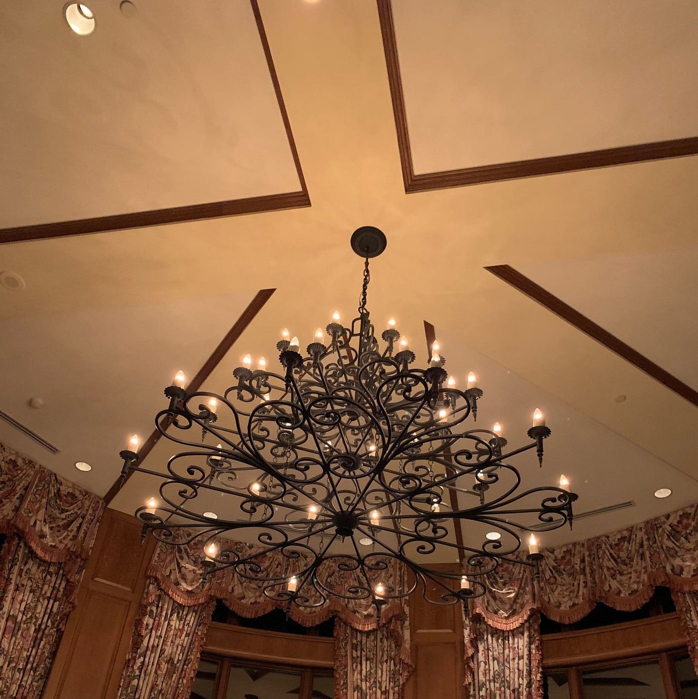 Ornate wrought-iron chandelier beneath the lounge's vaulted, beamed ceiling
