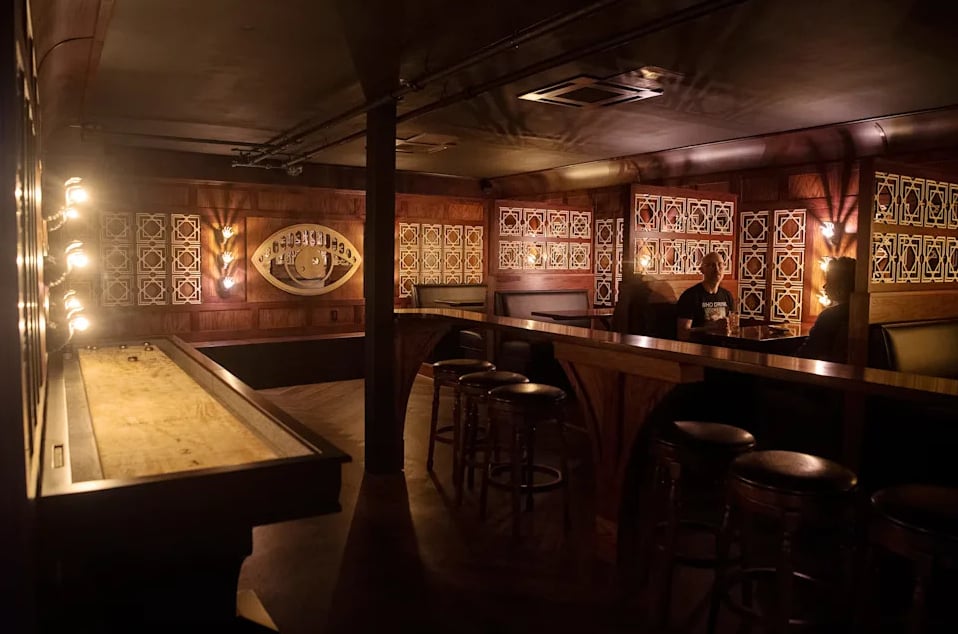 Lively evening at the bar with guests, hanging stemware canopy, and warm ambiance