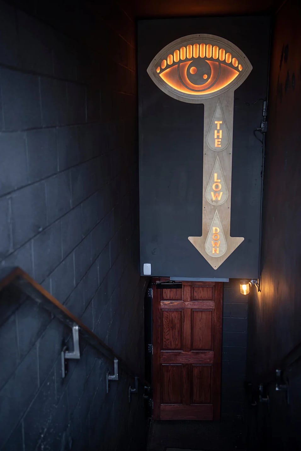 The iconic eye-and-arrow neon sign beckoning guests down to The Low Down.