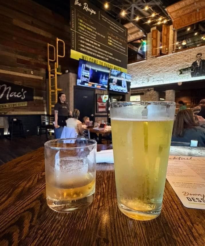 Fresh pints and cocktails served at the rustic wooden bar featuring exposed brick walls.