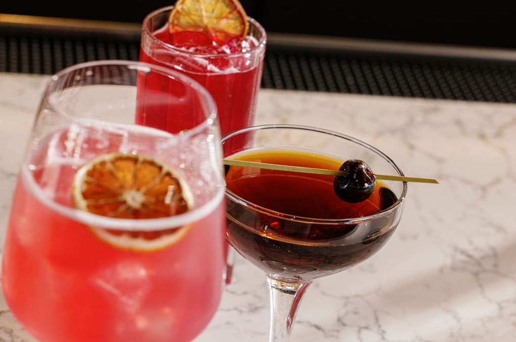 Signature cocktails served at the bar including a Manhattan and citrus-infused gin drinks.