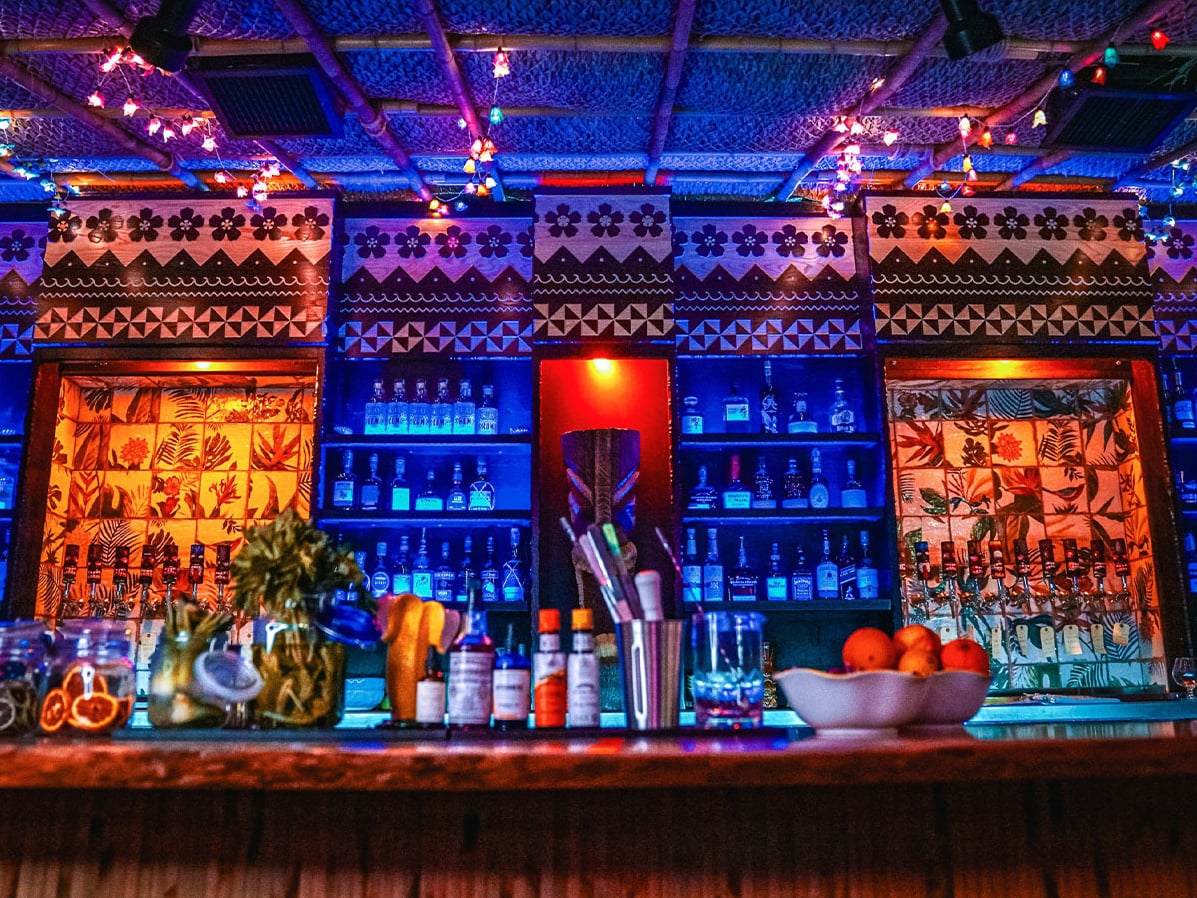 Tiki-carved backbar panels and backlit spirits shelf showcase the bar's dramatic decor.