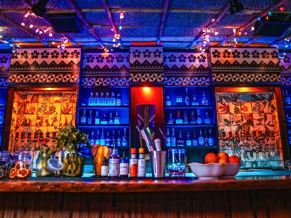 Intricate hand-carved tiki panels and colorful backbar lighting