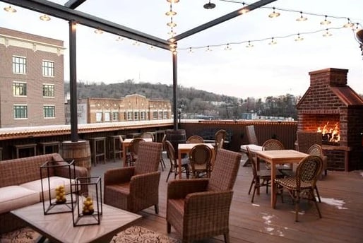 Rooftop patio with string lights, outdoor fireplace, and Asheville skyline views at Antidote