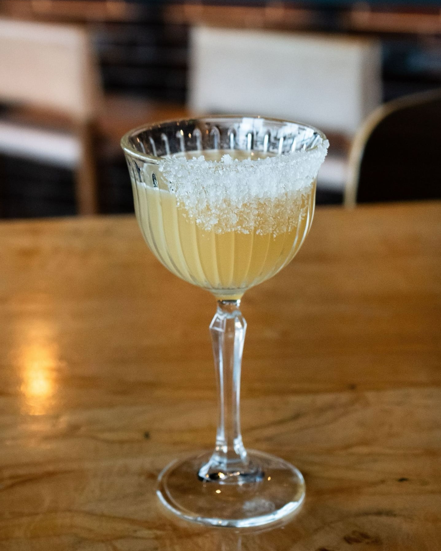 Elegant pale yellow cocktail featuring a sugar-rimmed coupe glass.