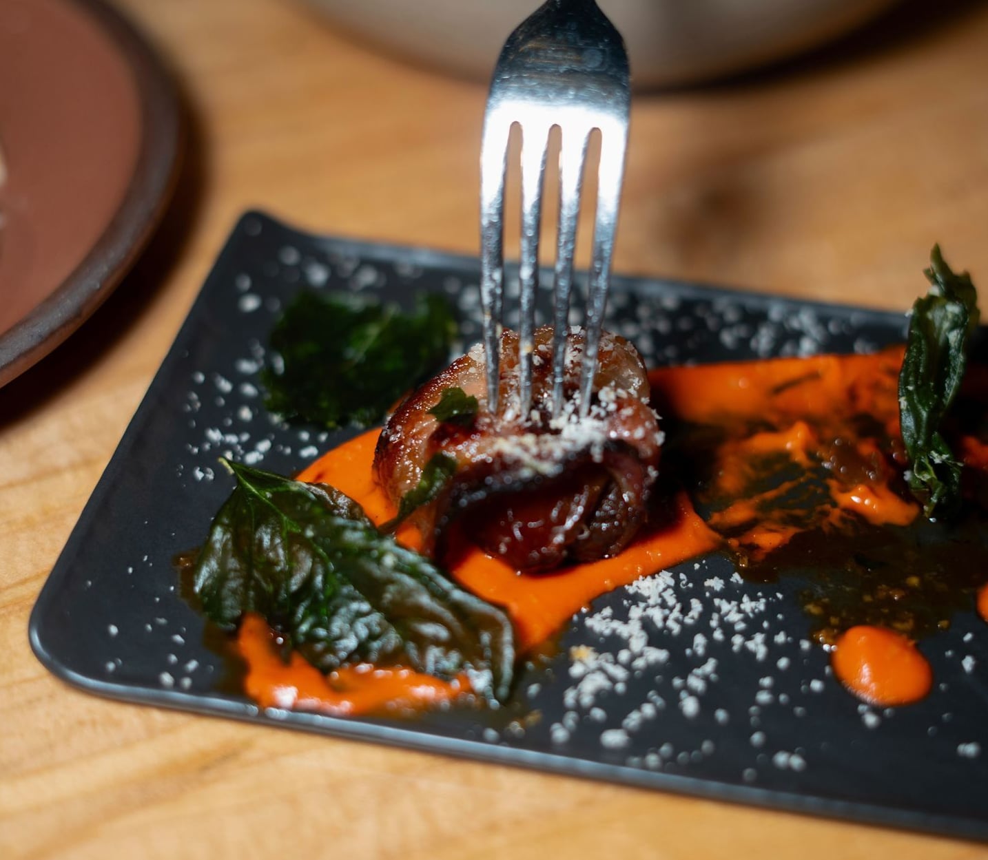 Plated appetizer featuring seared protein and roasted greens.