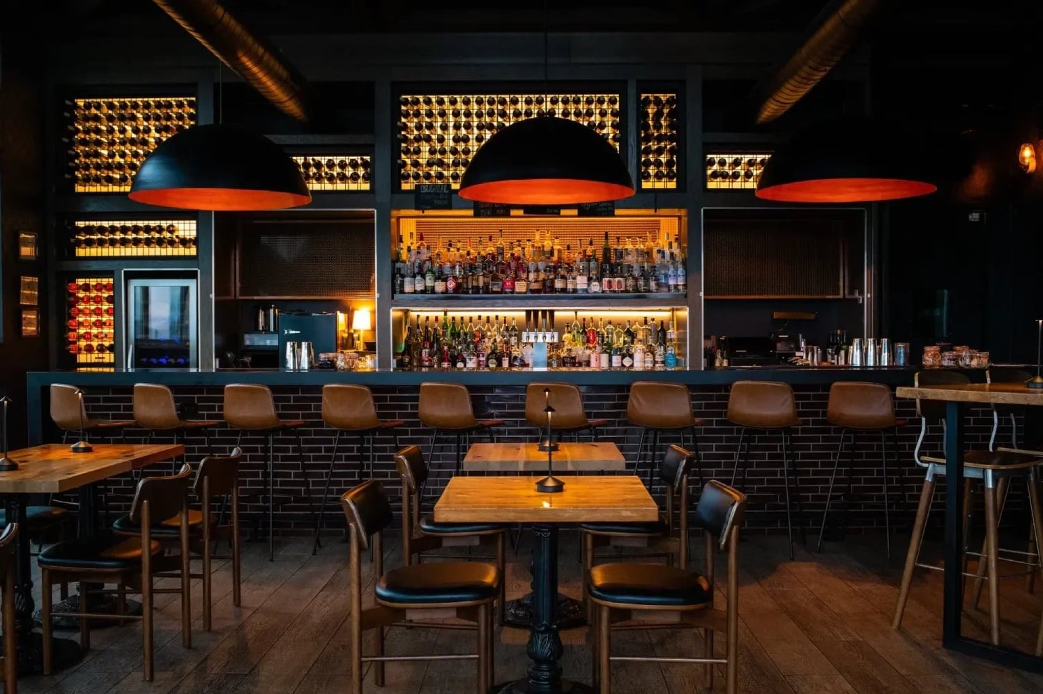 Stylish bar interior with exposed brick, ambient lighting, and full drink selection.
