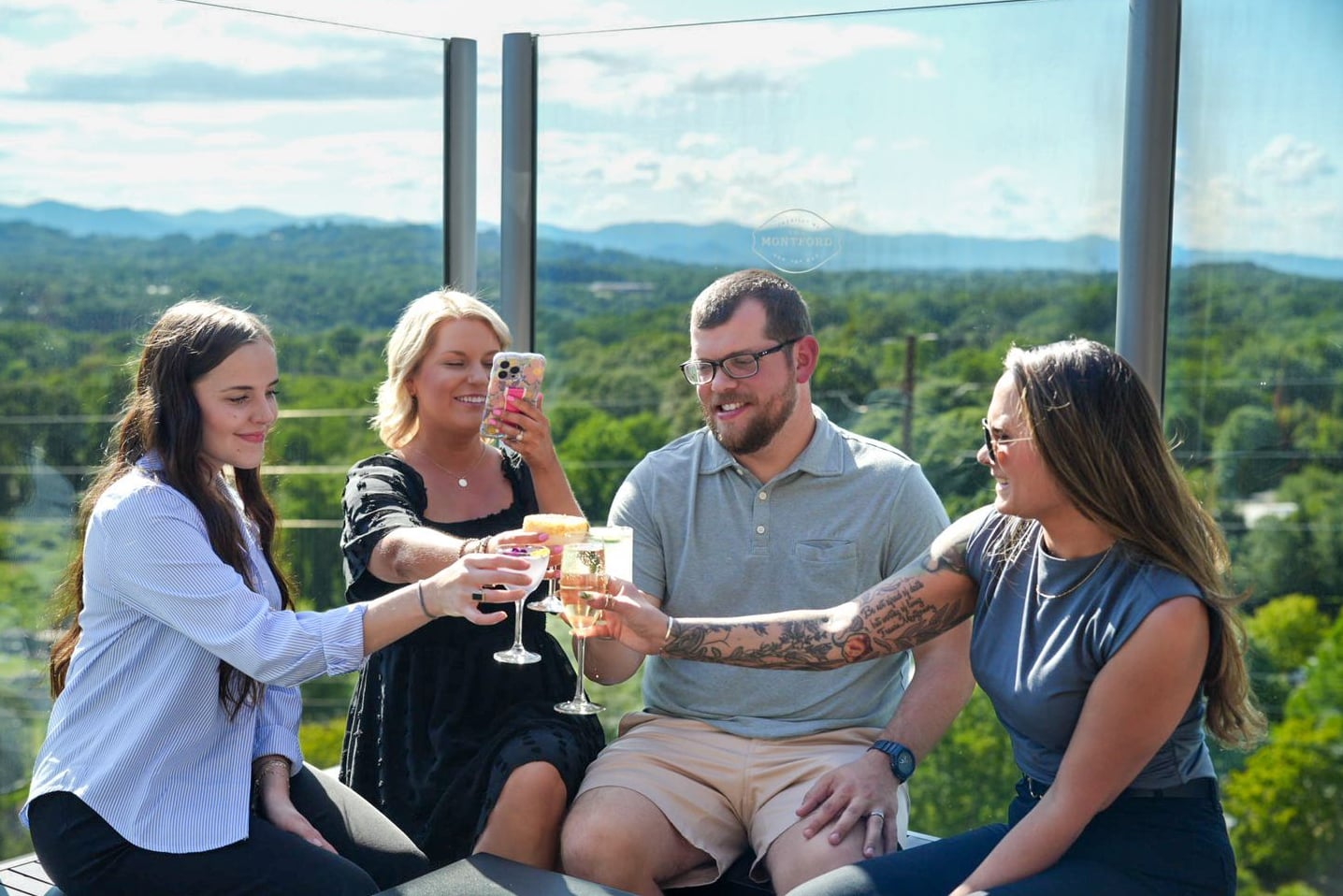 Friends enjoying cocktails on the rooftop terrace with panoramic mountain views.