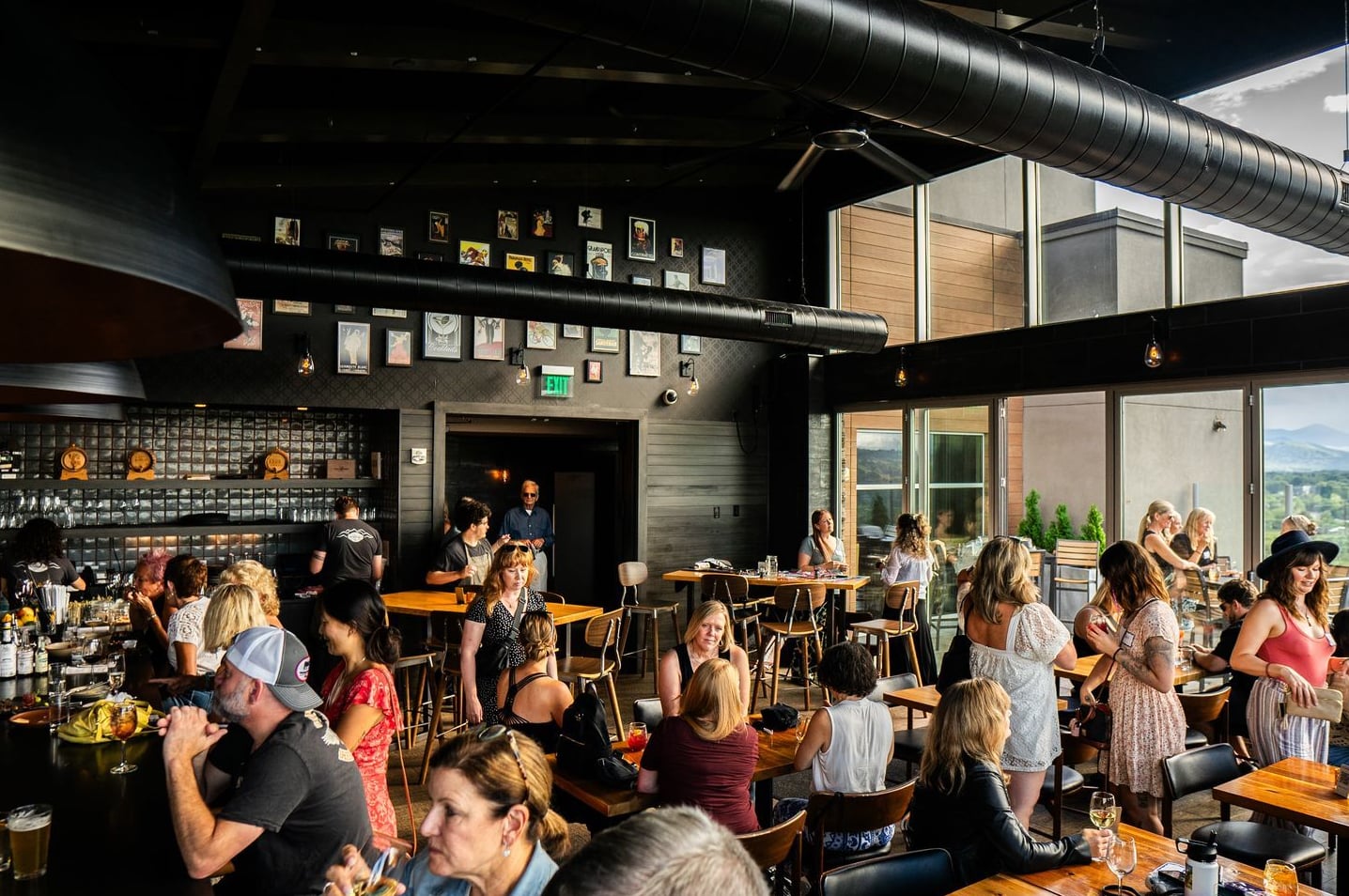 Bustling interior of the bar with industrial decor and scenic views.