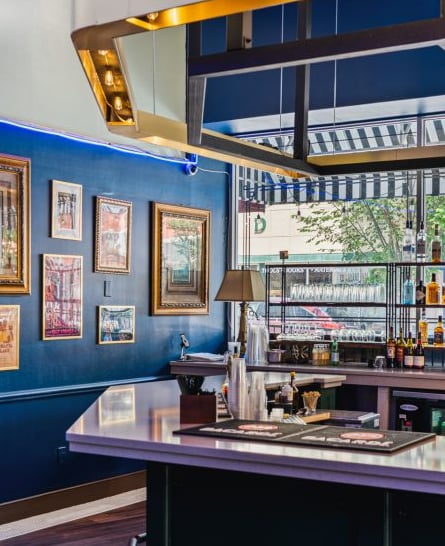 Stylish bar interior featuring navy blue walls and curated gallery-style artwork.
