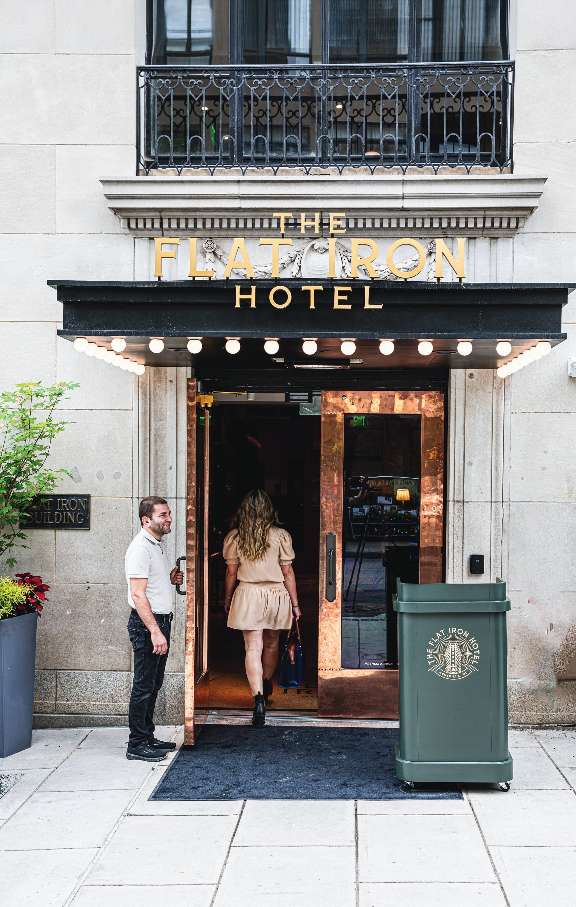 The Flat Iron Hotel entrance with gold marquee signage and doorman