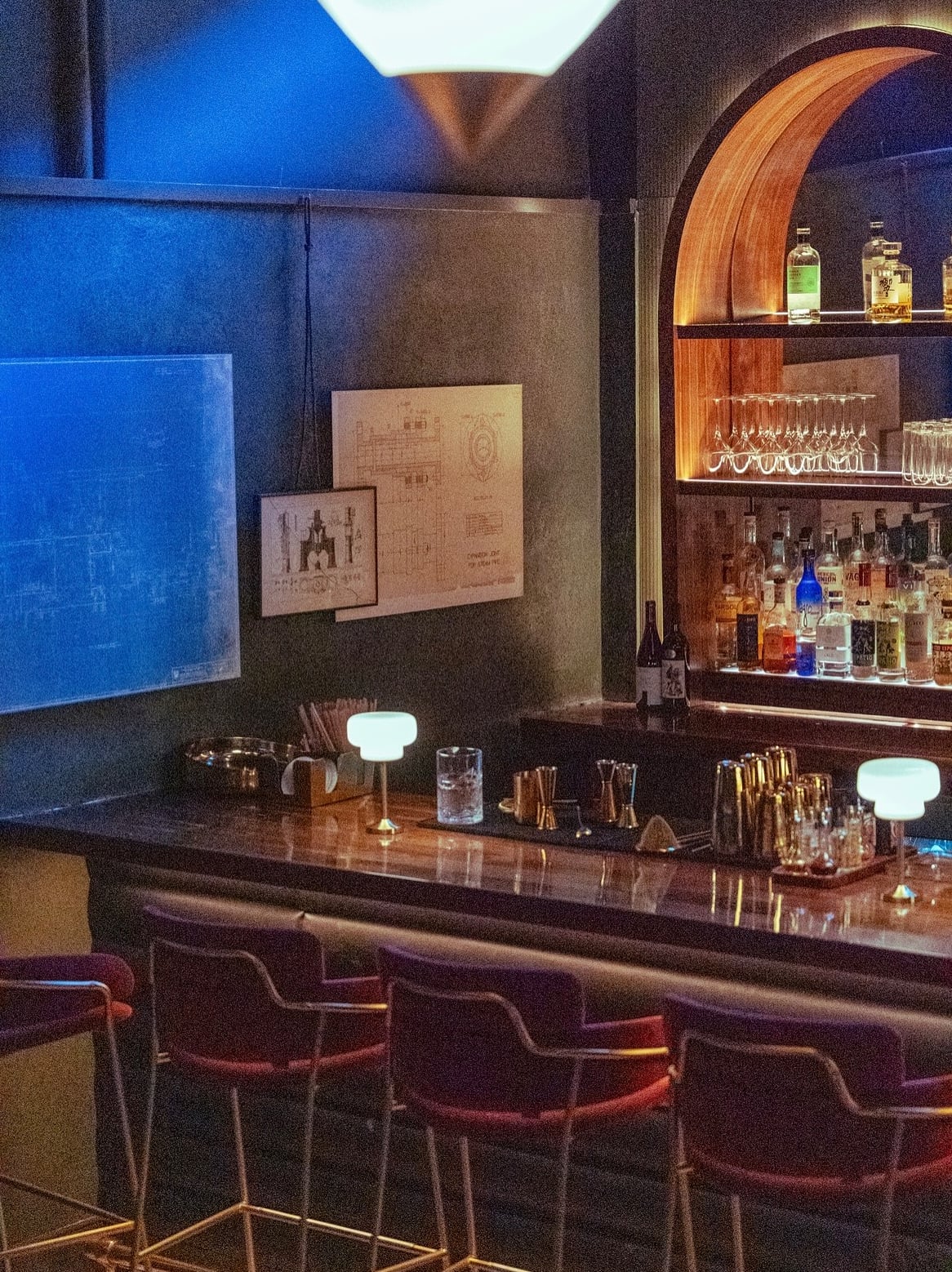 Sophisticated bar interior with custom arched backbar and moody blue accent lighting