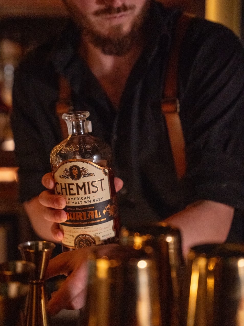Bartender showcasing premium Chemist whiskey selection