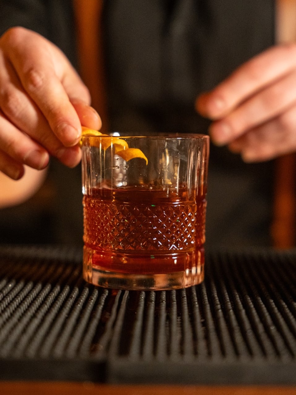 Master craftsmanship: orange peel garnish on amber cocktail