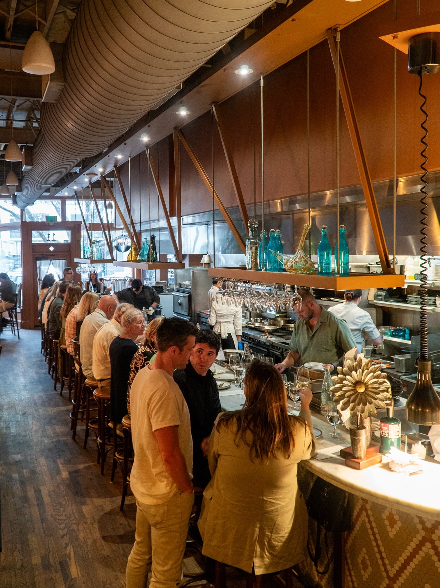 Busy open-concept interior with exposed wood beams and stainless steel kitchen views.