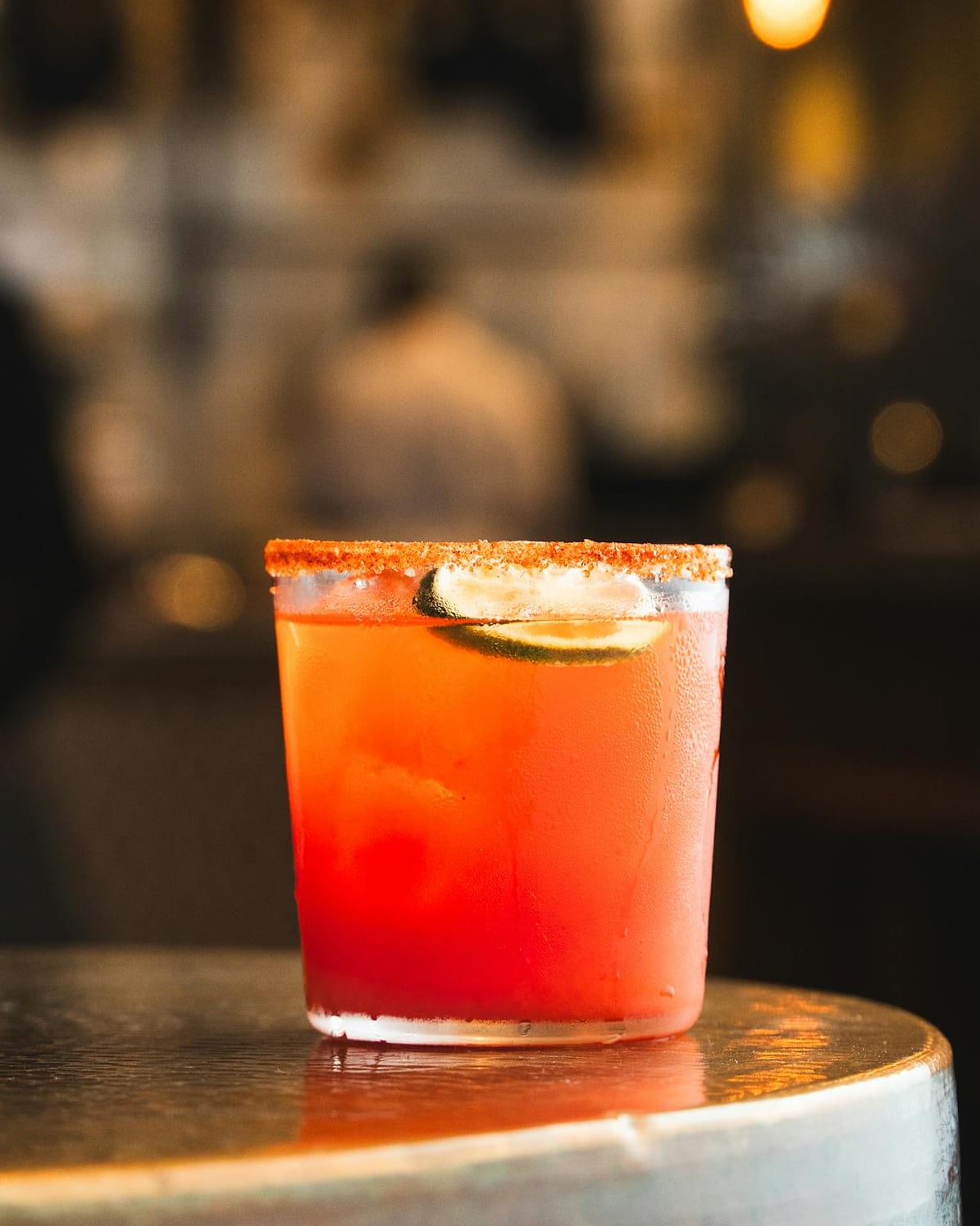Signature orange cocktail with salted rim and lime garnish.