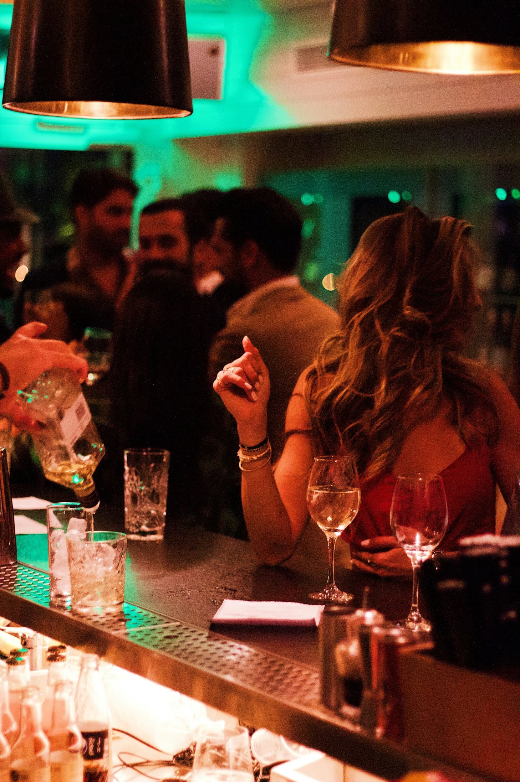 Lively bar atmosphere with guests and teal ambient lighting