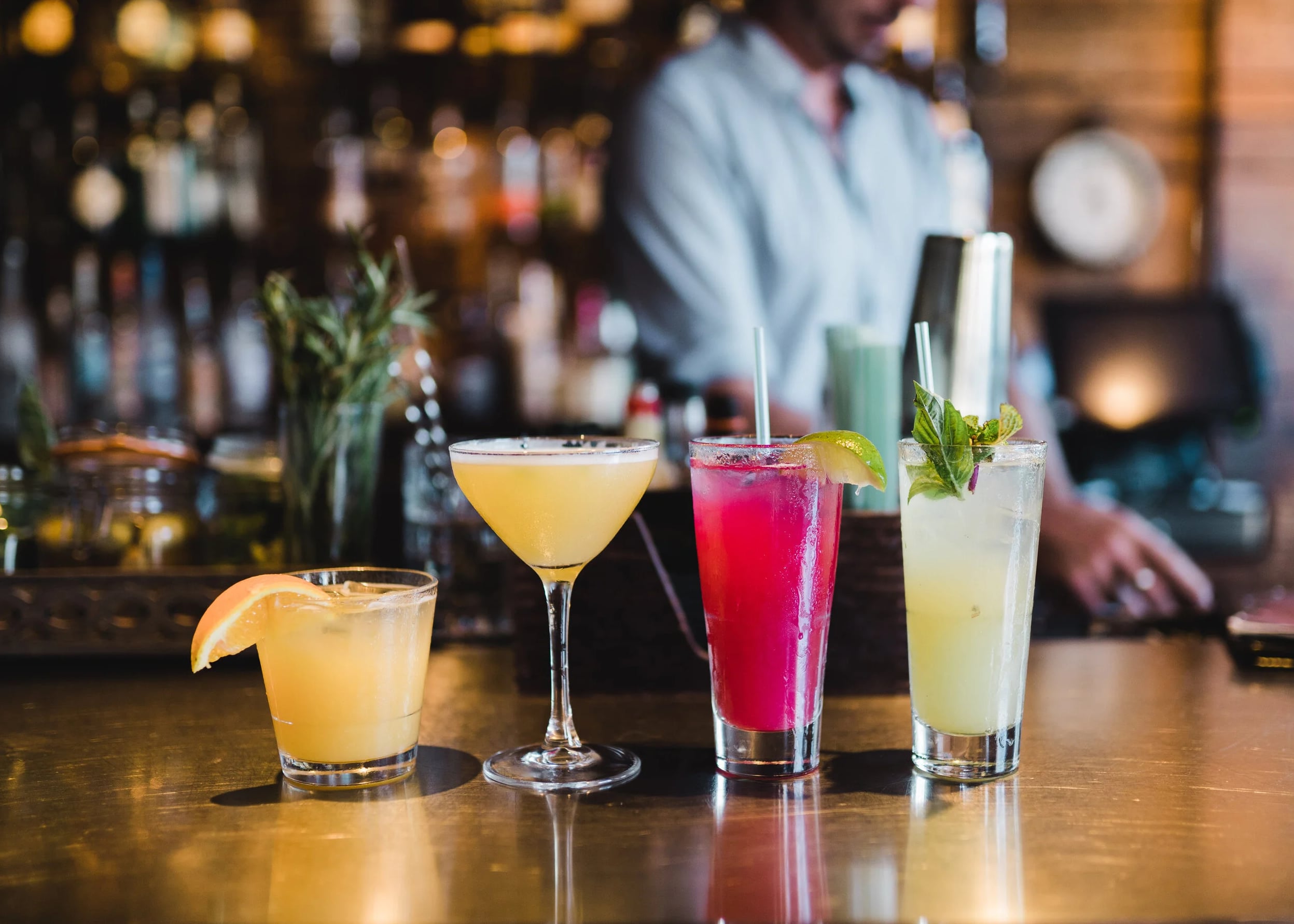 Four signature cocktails lined up at the bar — a sampler of The Social Lounge's craft drink menu.