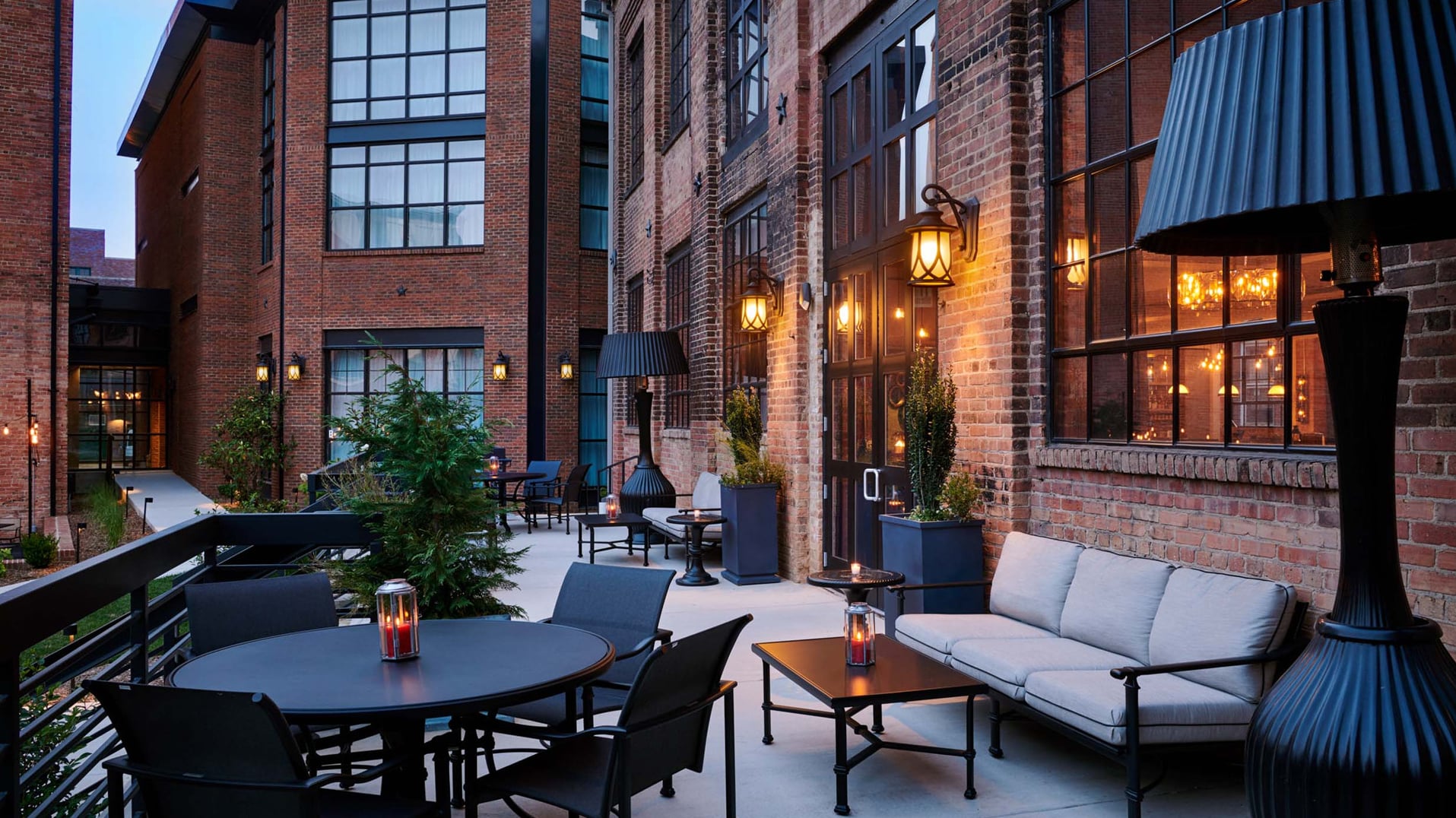 Stylish outdoor courtyard patio with exposed brick walls and ambient evening lighting.