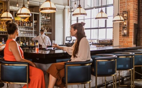 Guests enjoying cocktails at the Workshop Lounge bar with bartender at work.