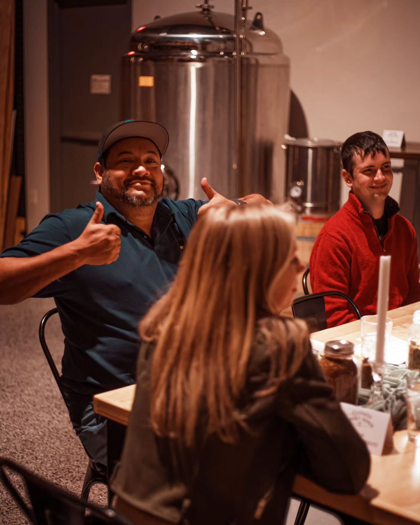 Visitors enjoying a tasting experience amidst the brewery's fermentation tanks.