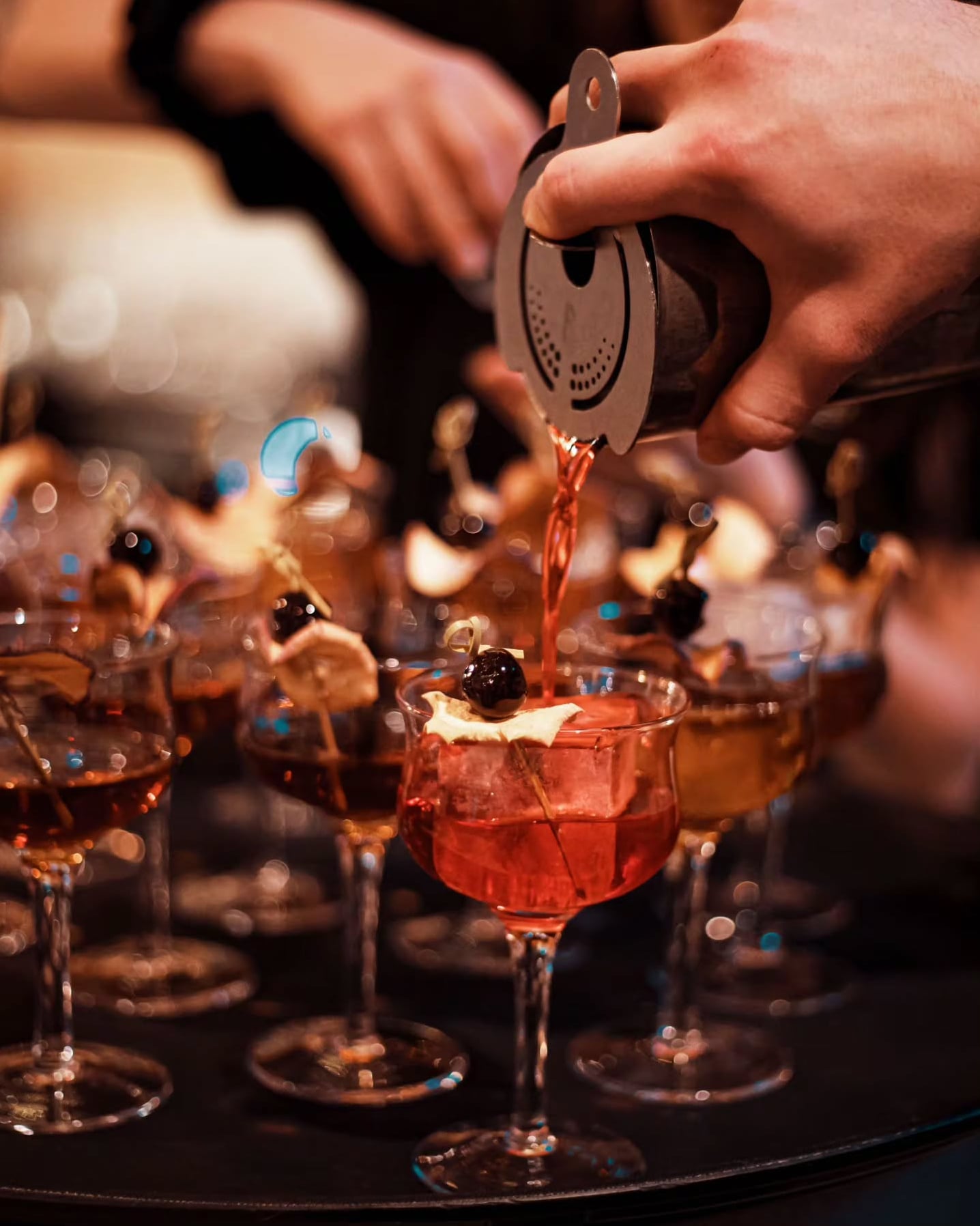 Freshly strained signature cocktails garnished with olives and cheese chips served at the bar.
