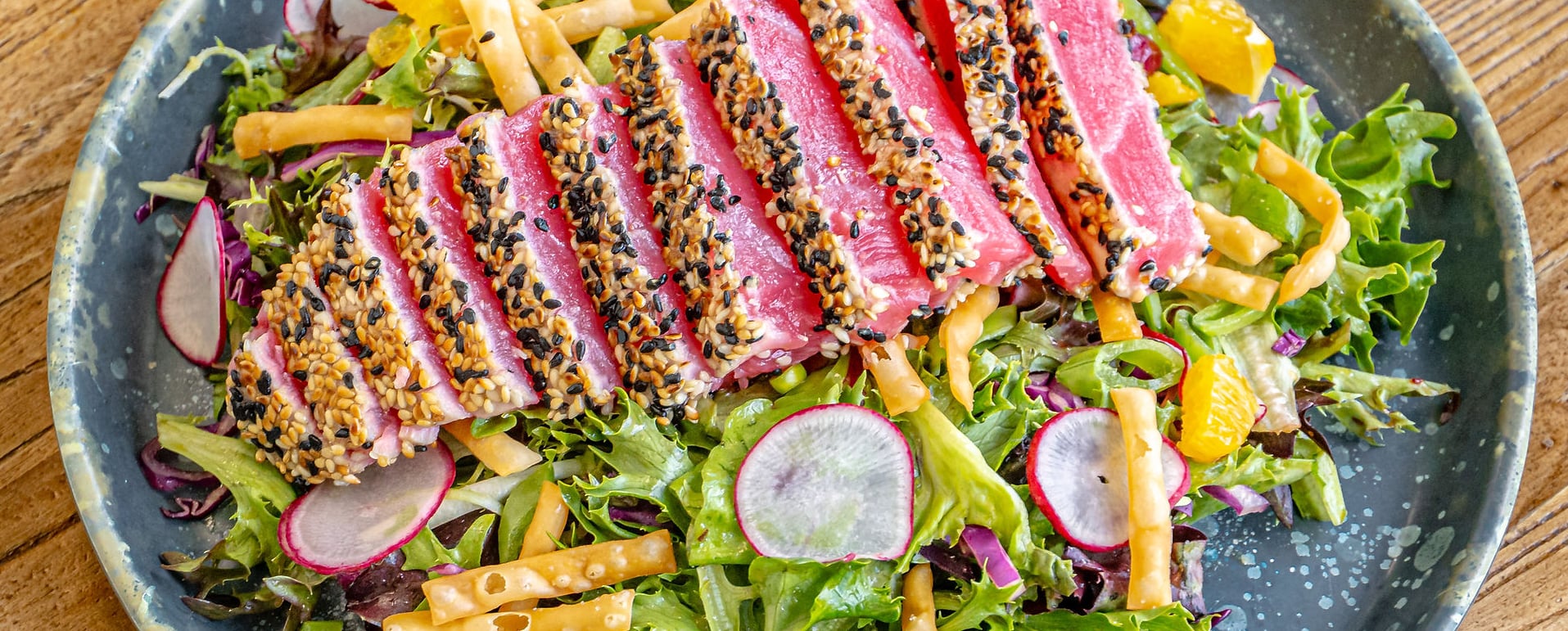 Sesame-crusted seared tuna with fresh greens and radish salad.