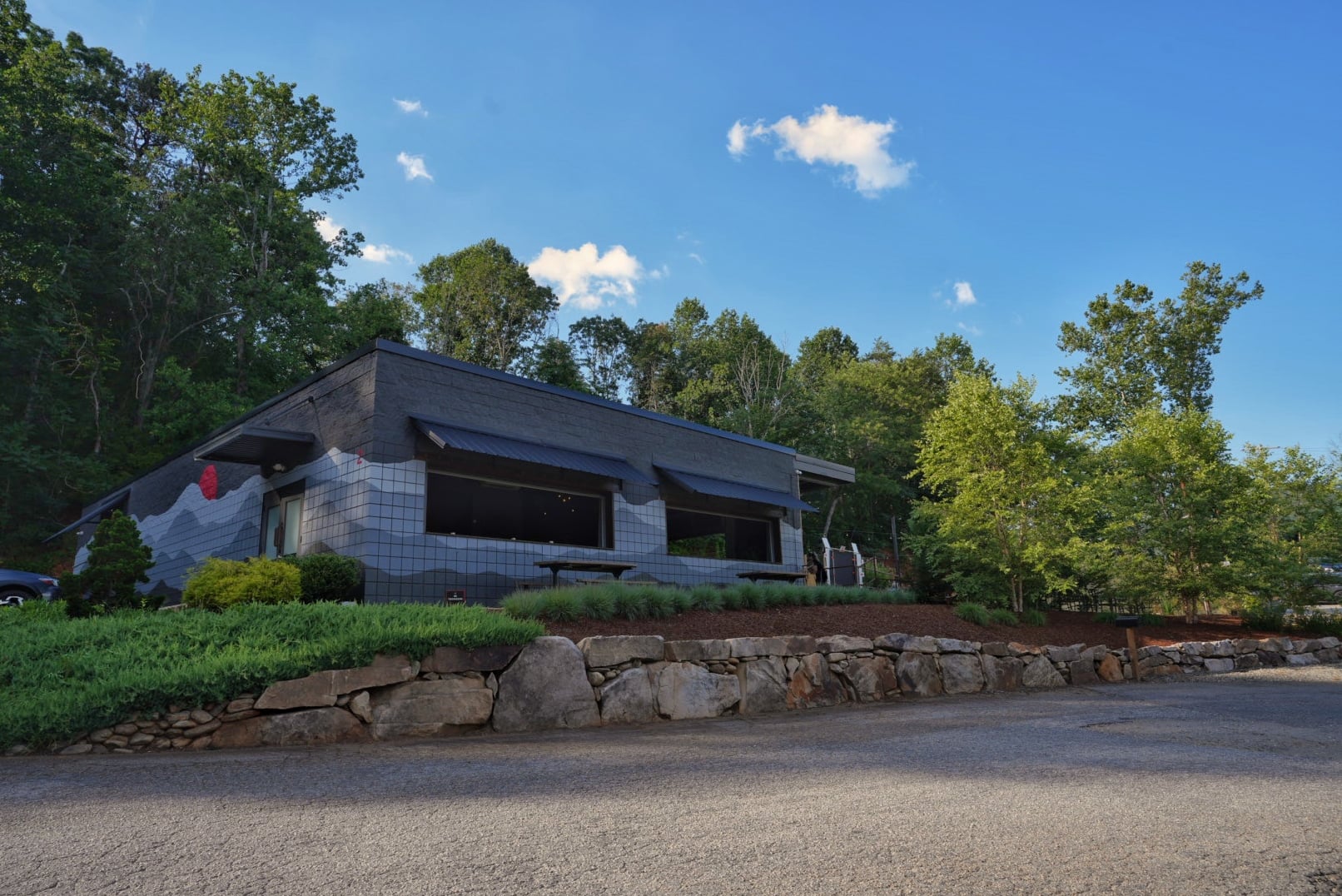 Modern exterior of the lodge-style venue surrounded by trees.
