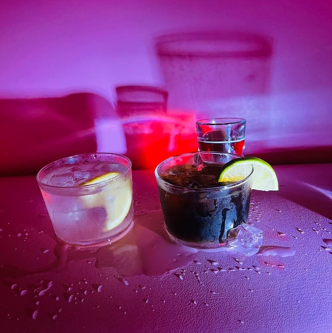 Cocktails on a table bathed in Strange Magic's signature purple-pink ambient glow