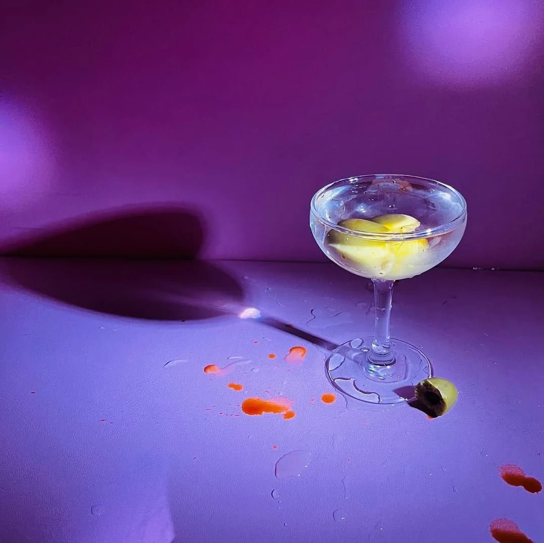 Signature martini glowing under Strange Magic's purple lighting