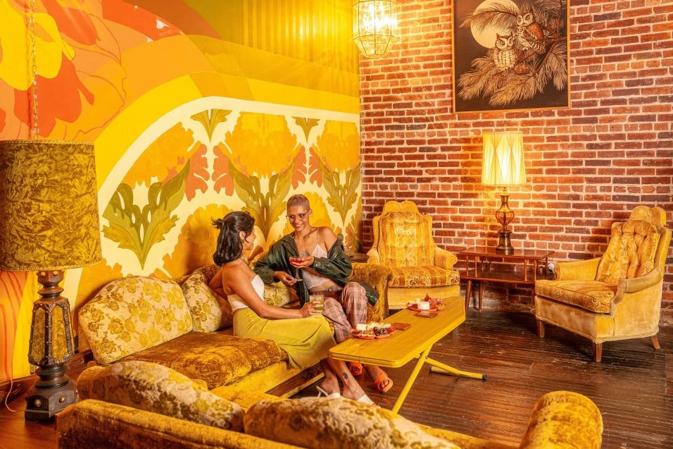 DayTrip's sunny yellow vintage lounge room with velvet chairs and floral wallpaper