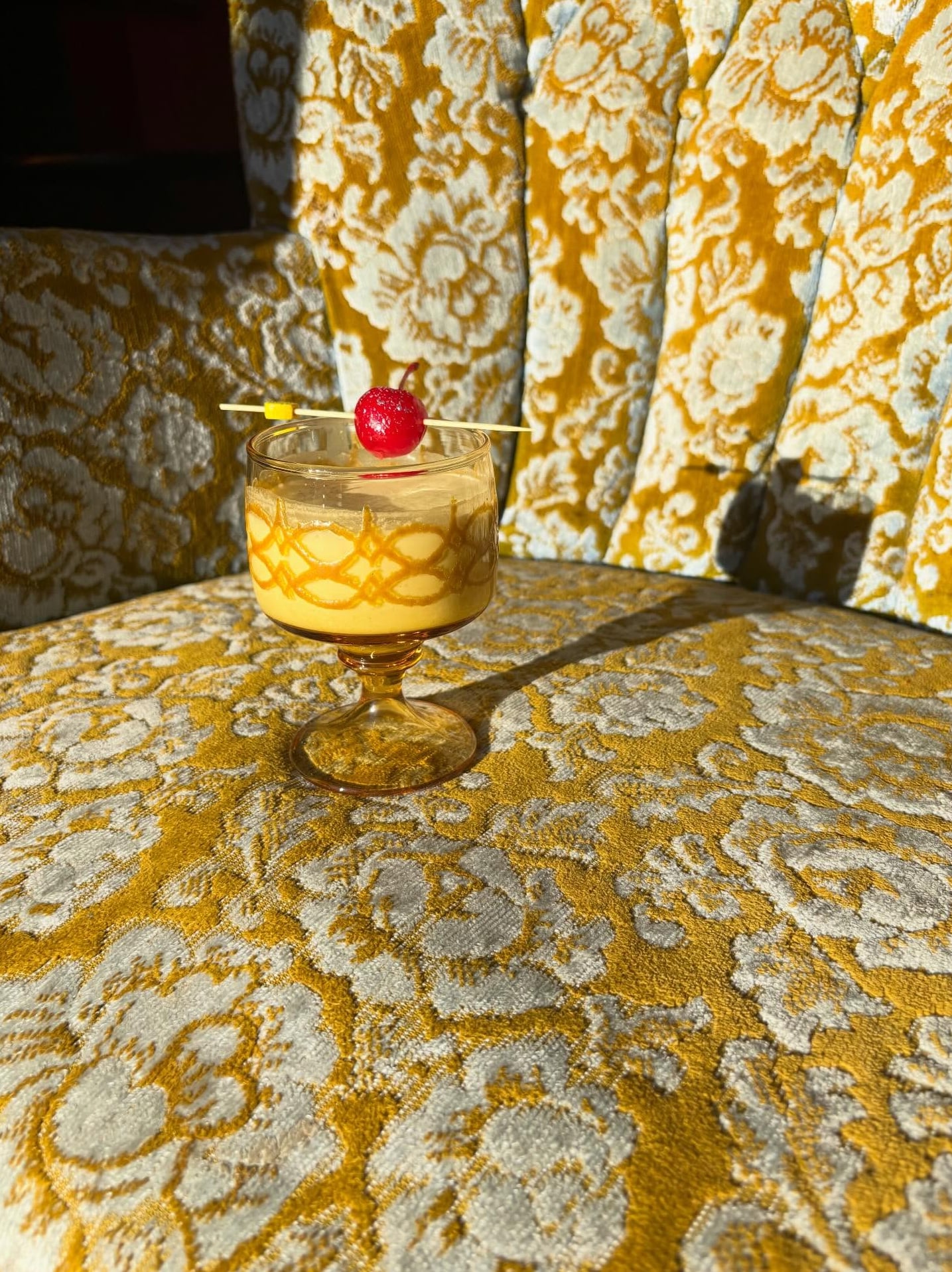 Signature yellow cocktail served on vintage velvet seating.