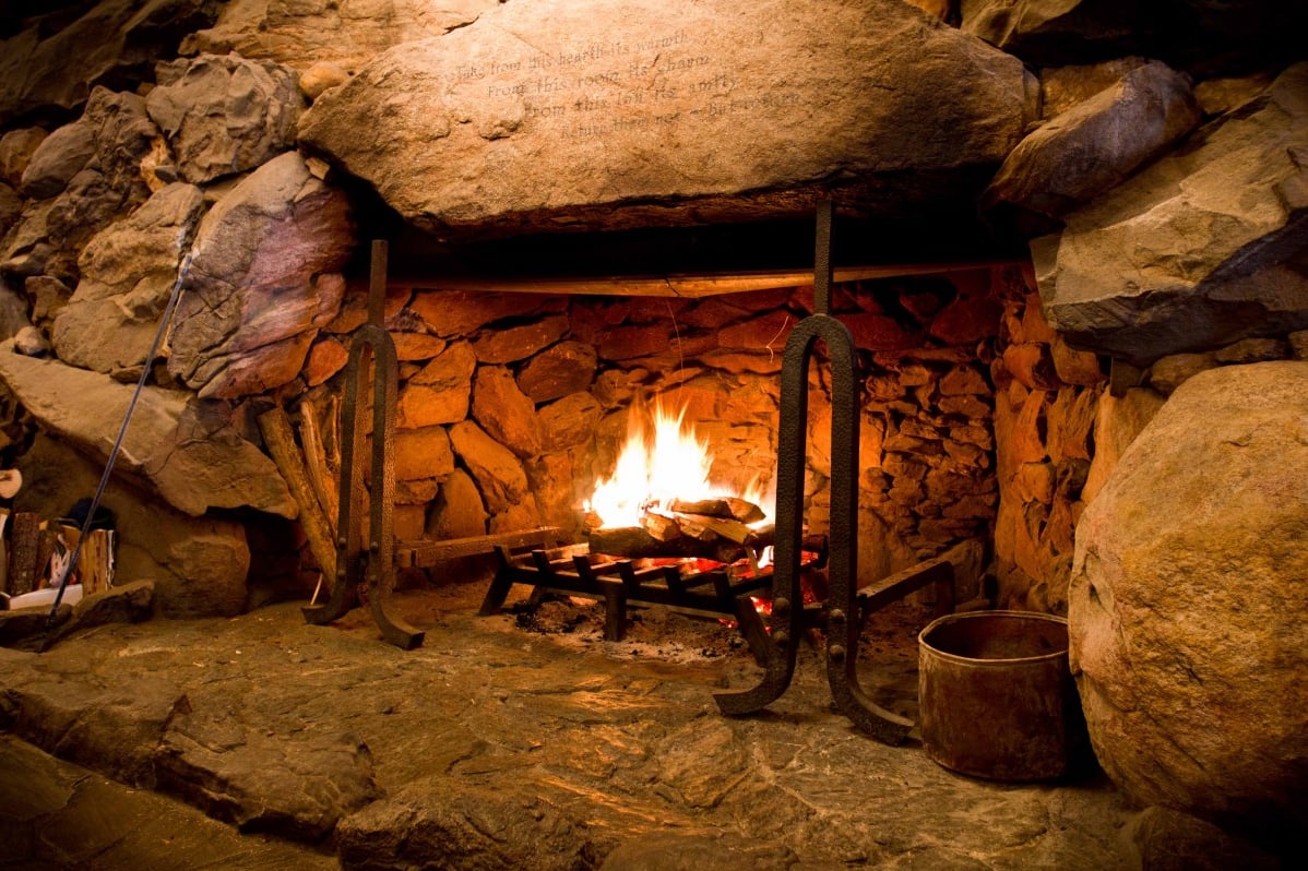 The Great Hall's massive granite fireplace roaring with fire — built entirely from mountain stone