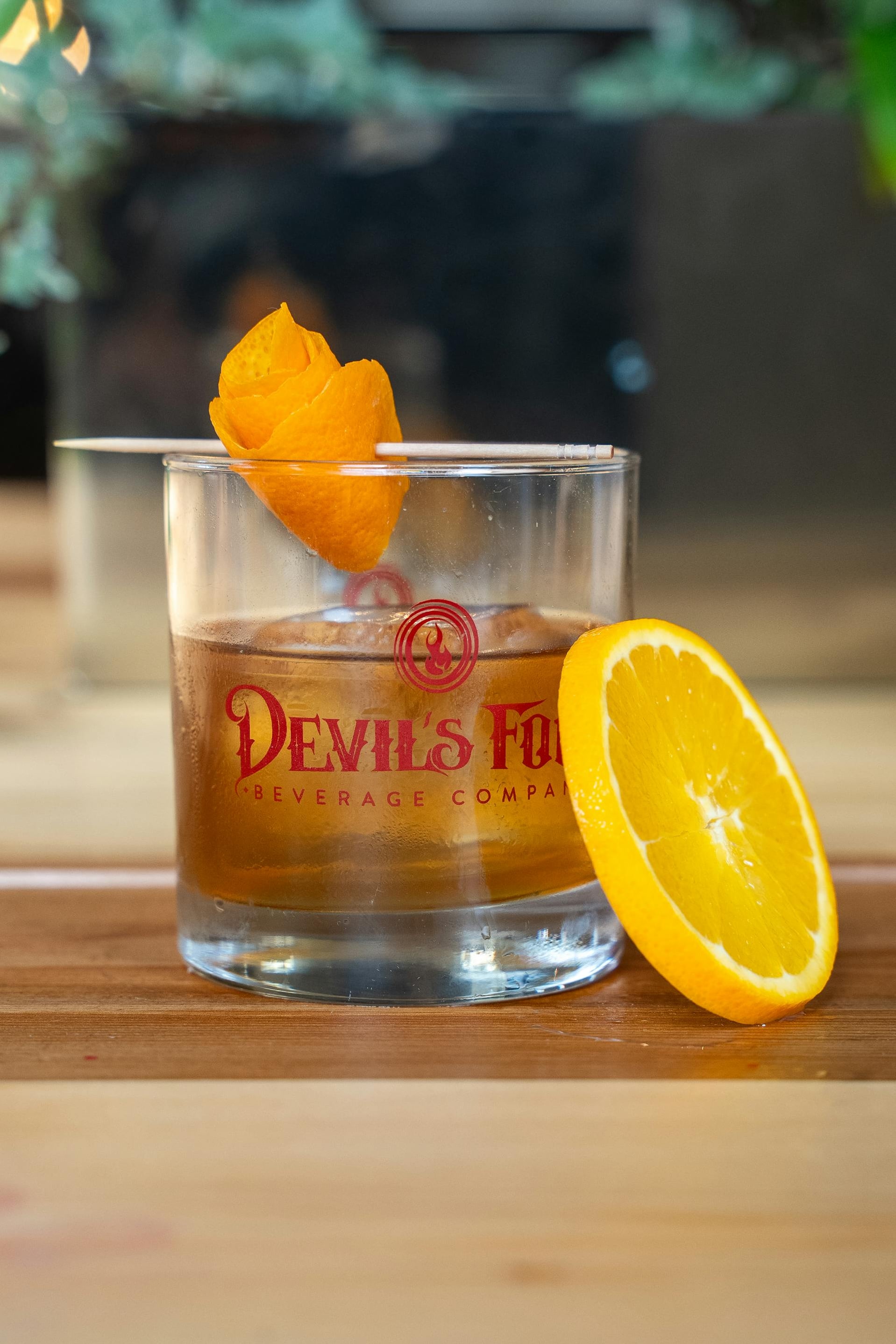Signature cocktail featuring an intricate orange rose garnish.