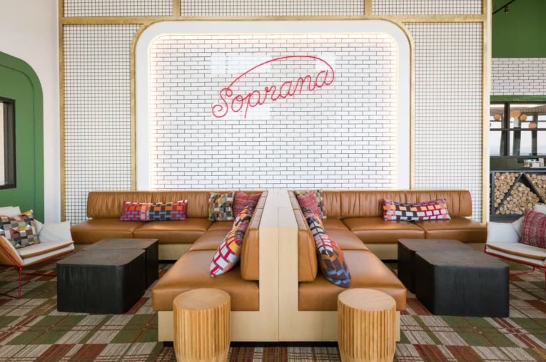 Contemporary lounge area featuring the Soprana neon sign with brown leather seating.