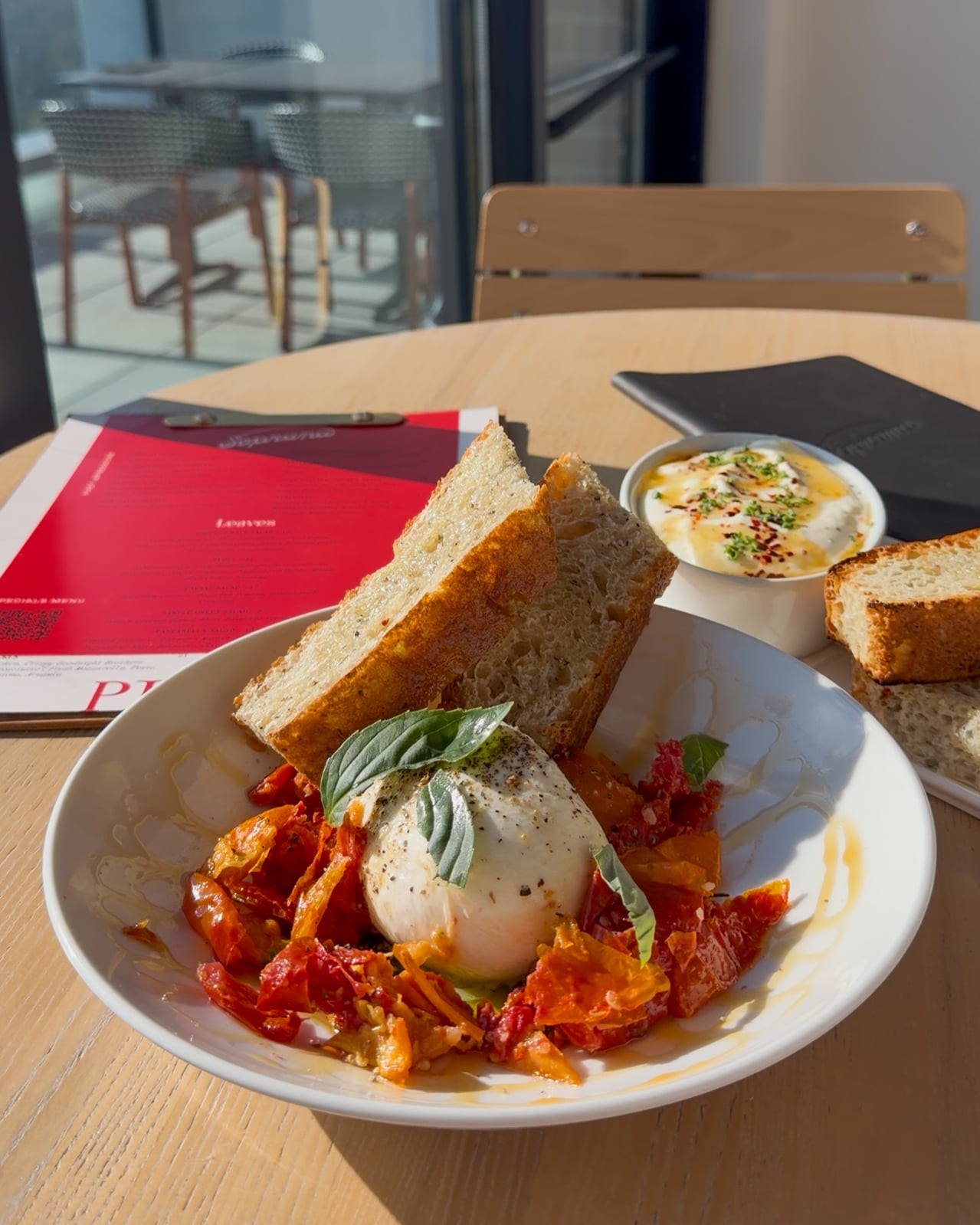 House-made burrata with roasted tomatoes and artisan toast, showcasing Soprana's Italian cucina heritage