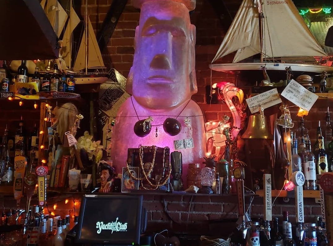 The iconic illuminated Easter Island moai behind the bar, surrounded by beer taps and nautical decor