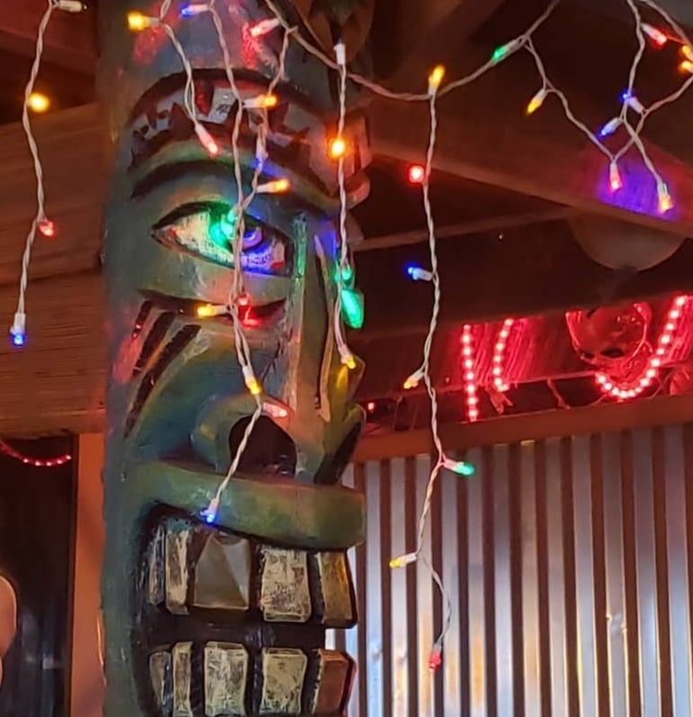 Tiki totem pole wrapped in colorful Christmas lights — a hallmark of the Asheville Yacht Club's eclectic dive bar decor