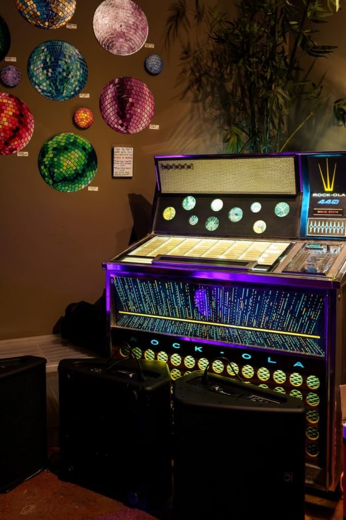 Vintage Rock-Ola jukebox with wall-mounted disco balls.