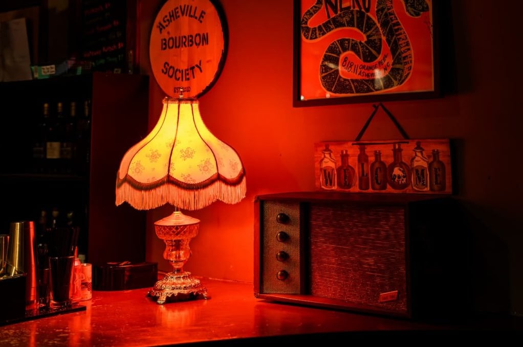 Vintage decor details with warm ambiance — Asheville Bourbon Society signage and antique lamp.