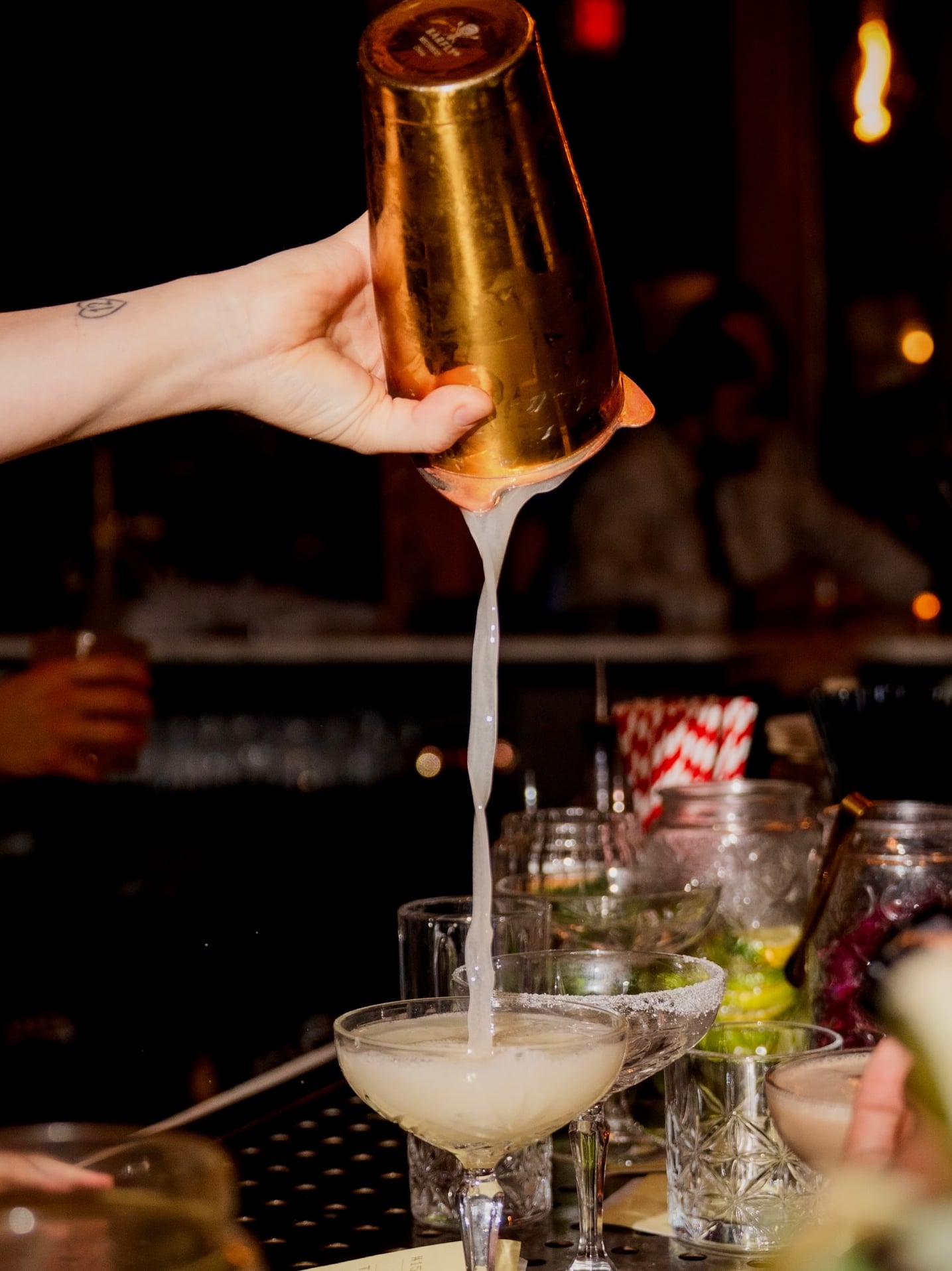 Handcrafted cocktail being poured from a golden shaker.