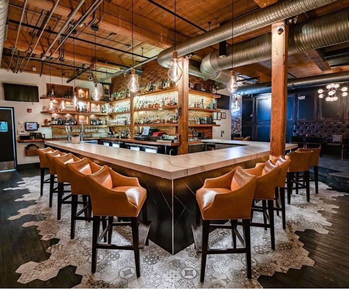 Rustic-industrial bar interior with custom leather seating and fully stocked open shelving